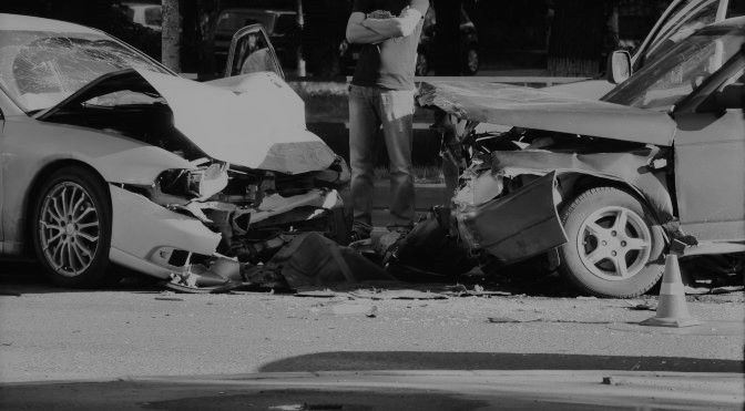 man standing between two wrecked cars after an accident